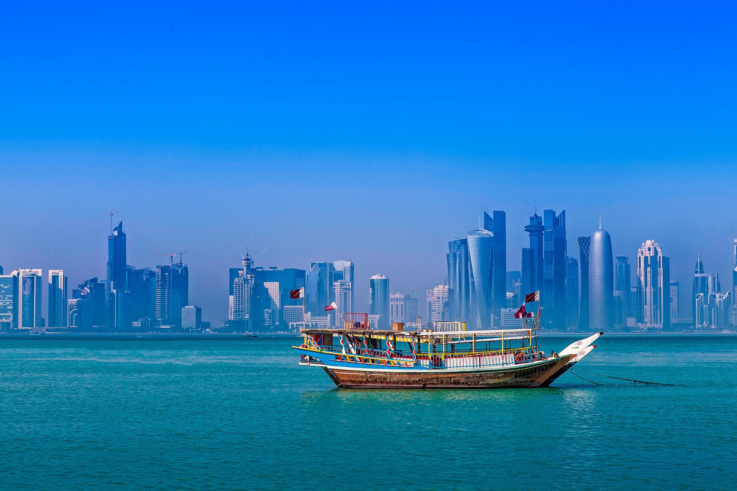 A traditional dhow boat against Doha's modern skyline over the Arabian Gulf.